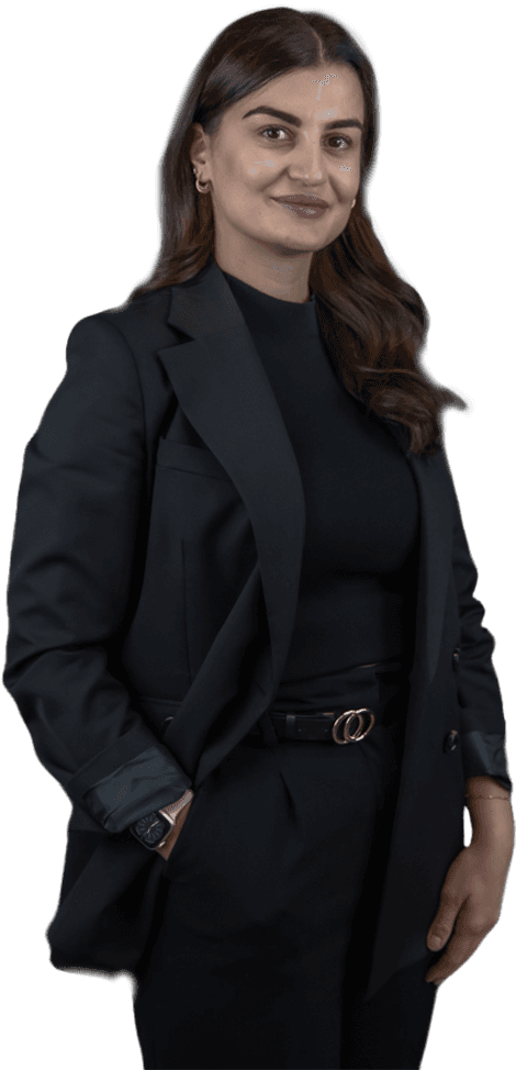 Persoon in zwarte blazer lacht vriendelijk naar je toe met een hand in de broekzak.